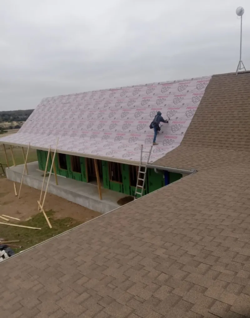 Worker preparing underlayment for a metal roof installation in Indio